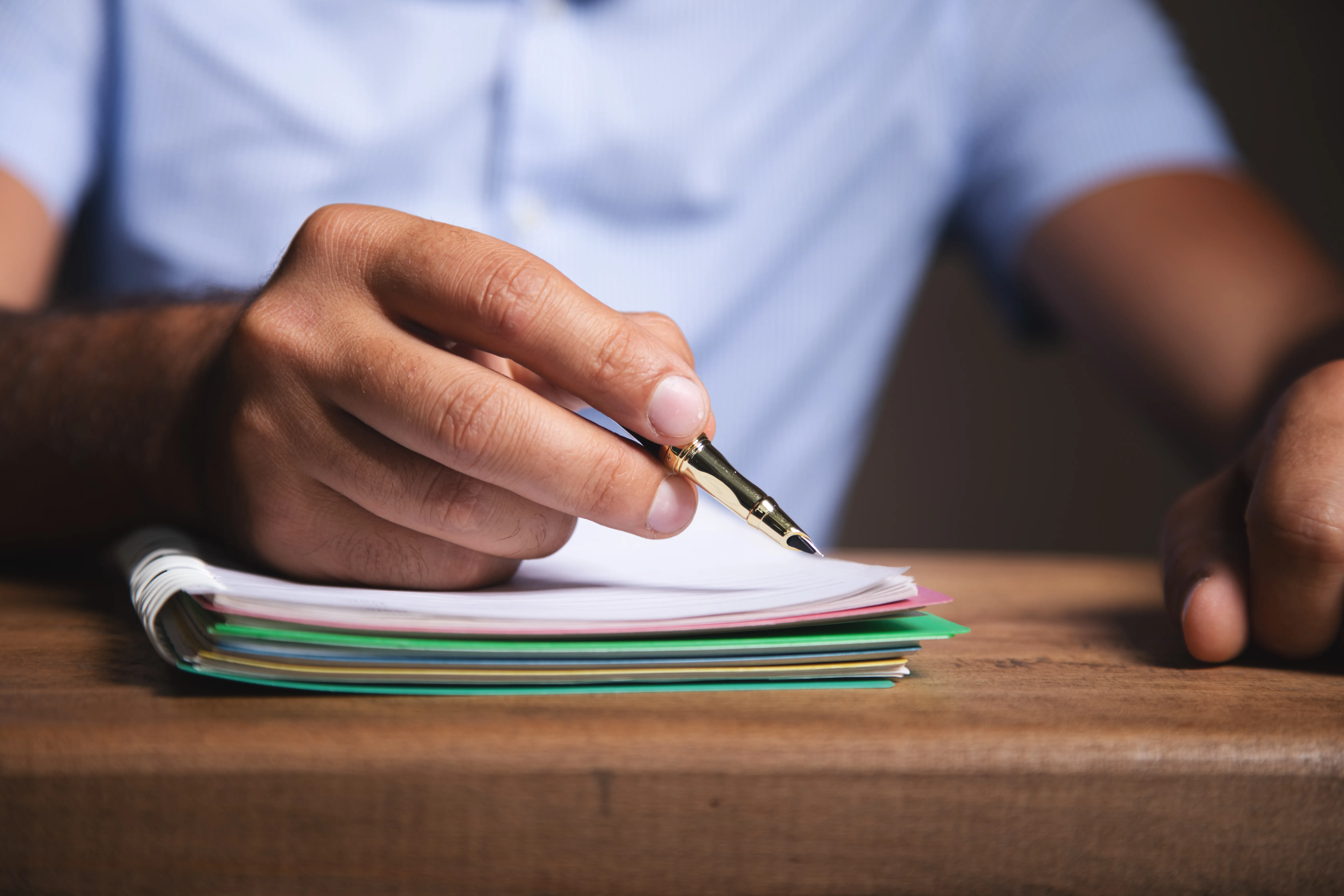 Person writing notes in a notebook during financial preparation