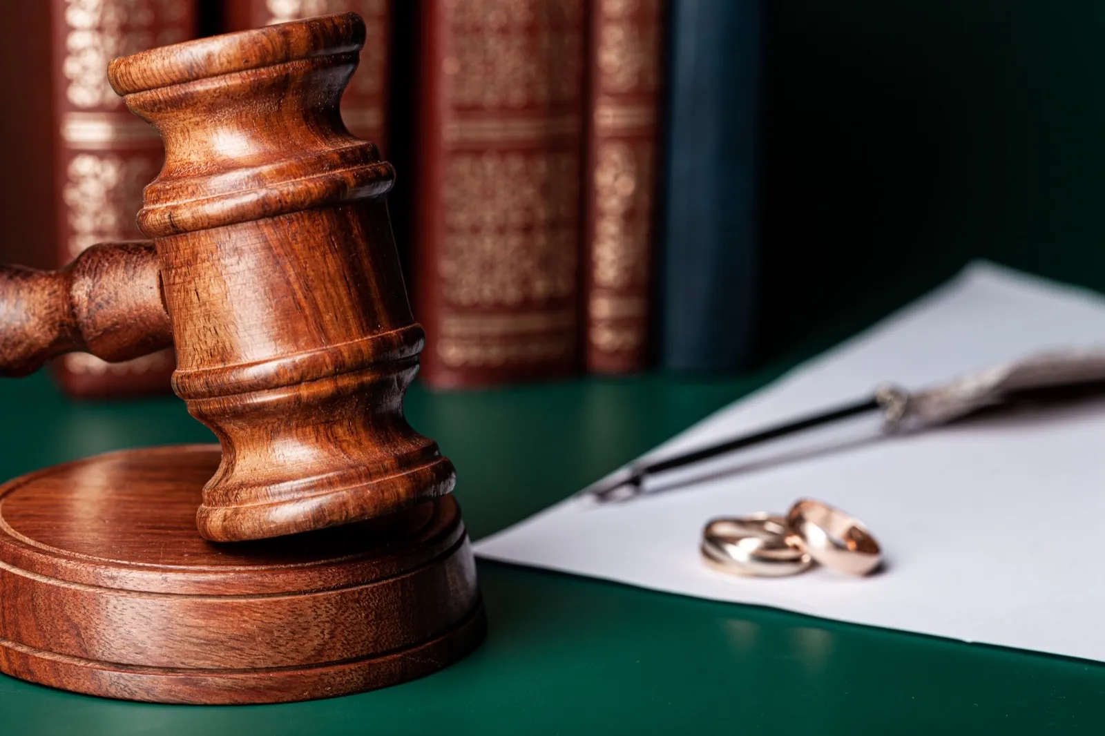 Judge's gavel beside wedding rings on a legal desk