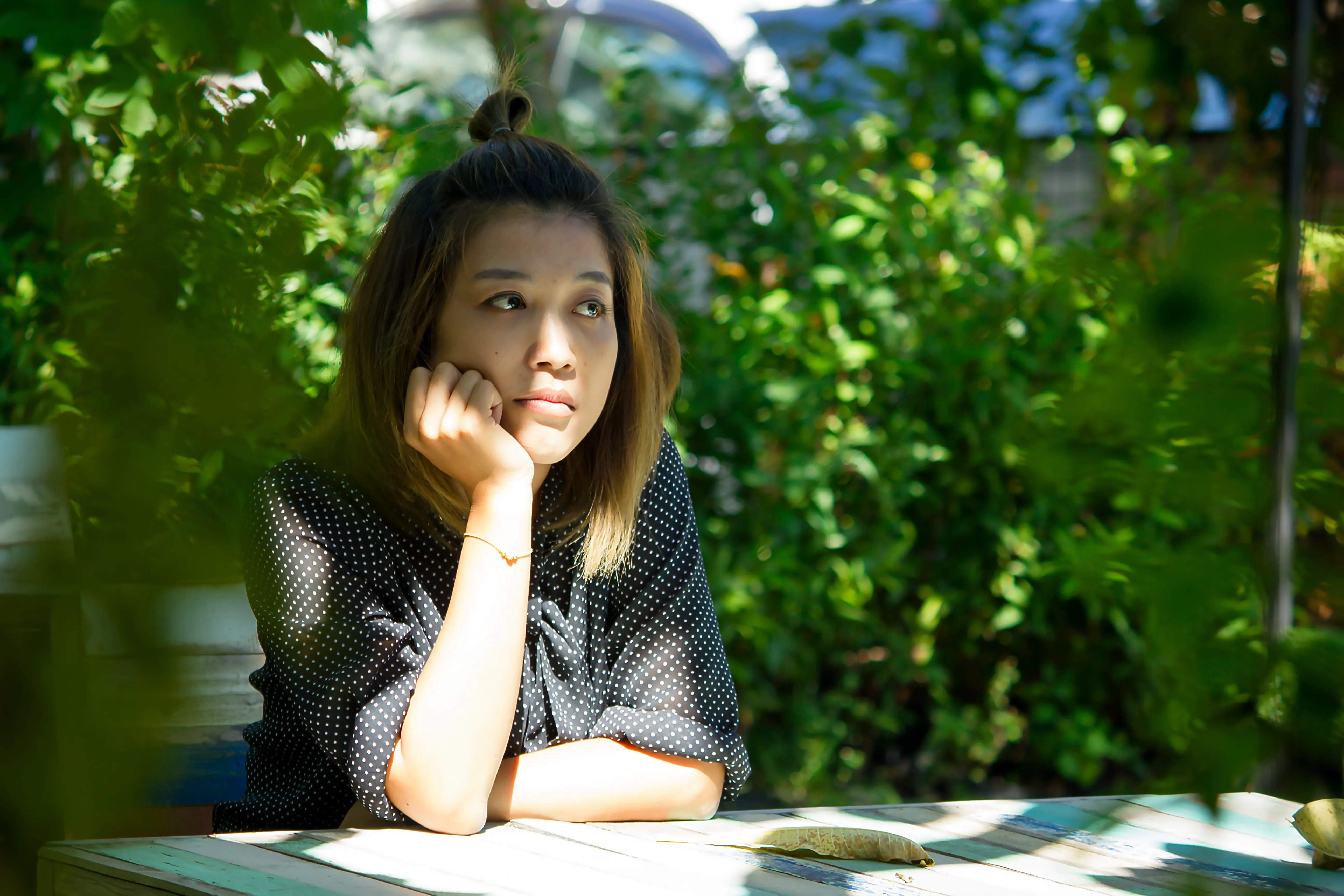 Woman sitting thoughtfully against plants