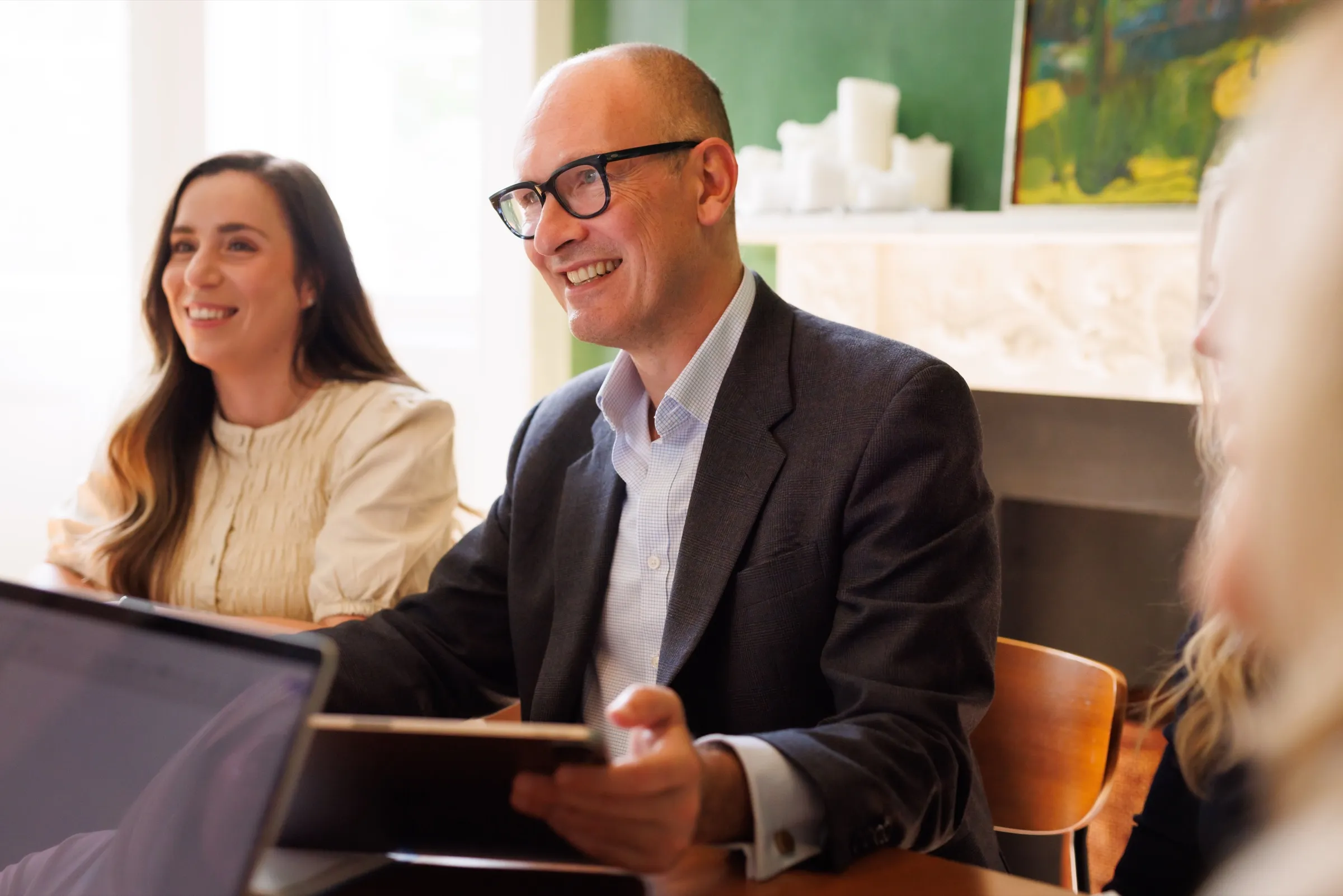 Lawyer and client smiling while reviewing a tablet together