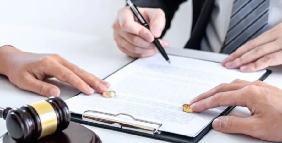 Two people signing legal documents with wedding rings and gavel, illustrating how marriage revokes a will