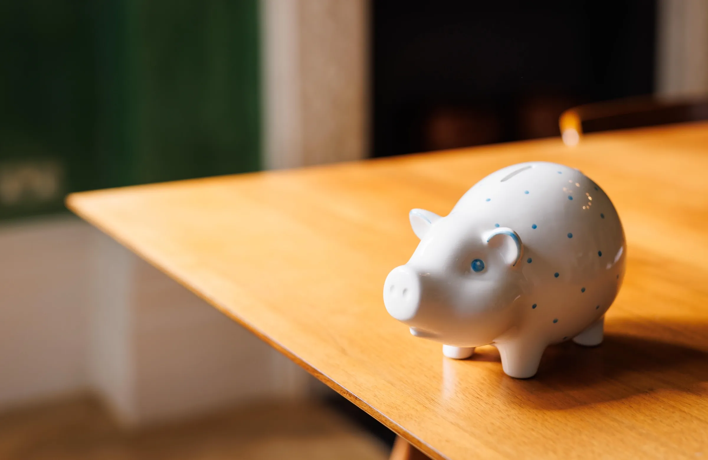 White ceramic piggy bank with blue dots on a wooden table