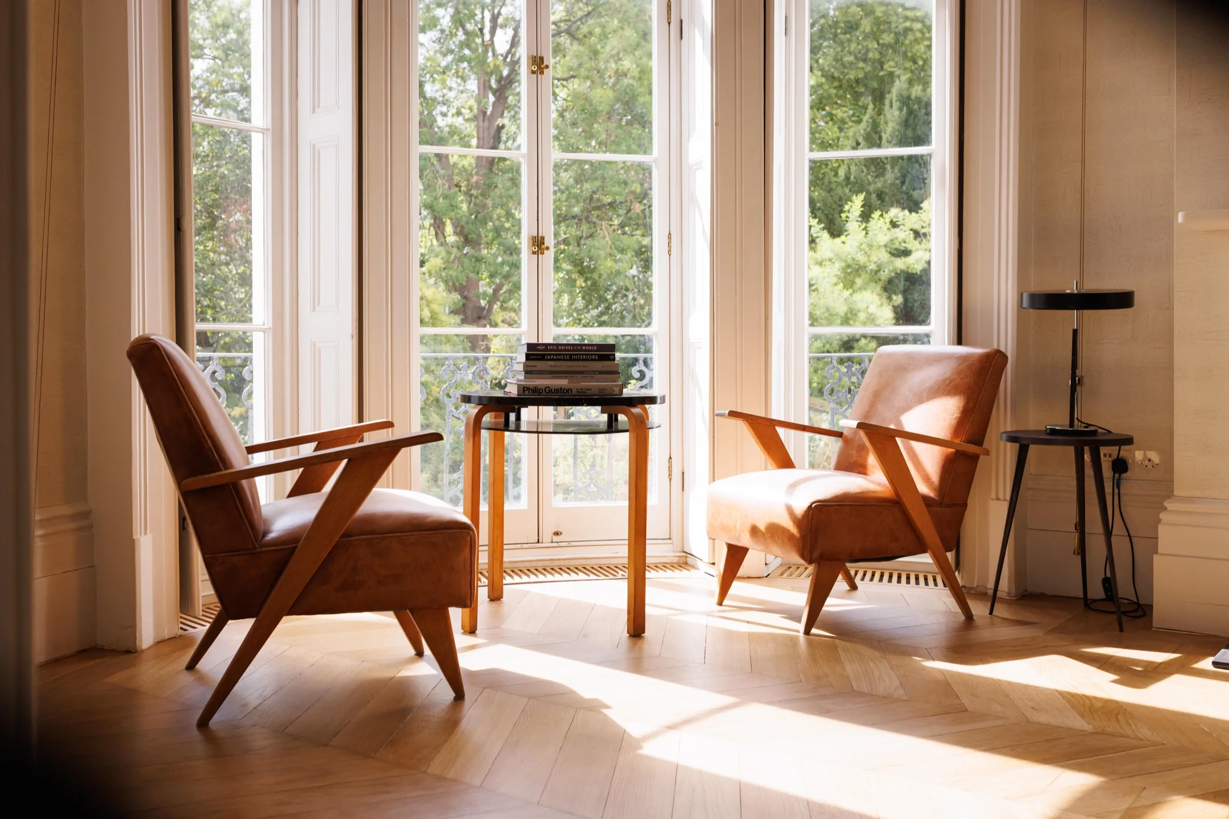 Sunlit consultation room with two leather armchairs by tall windows