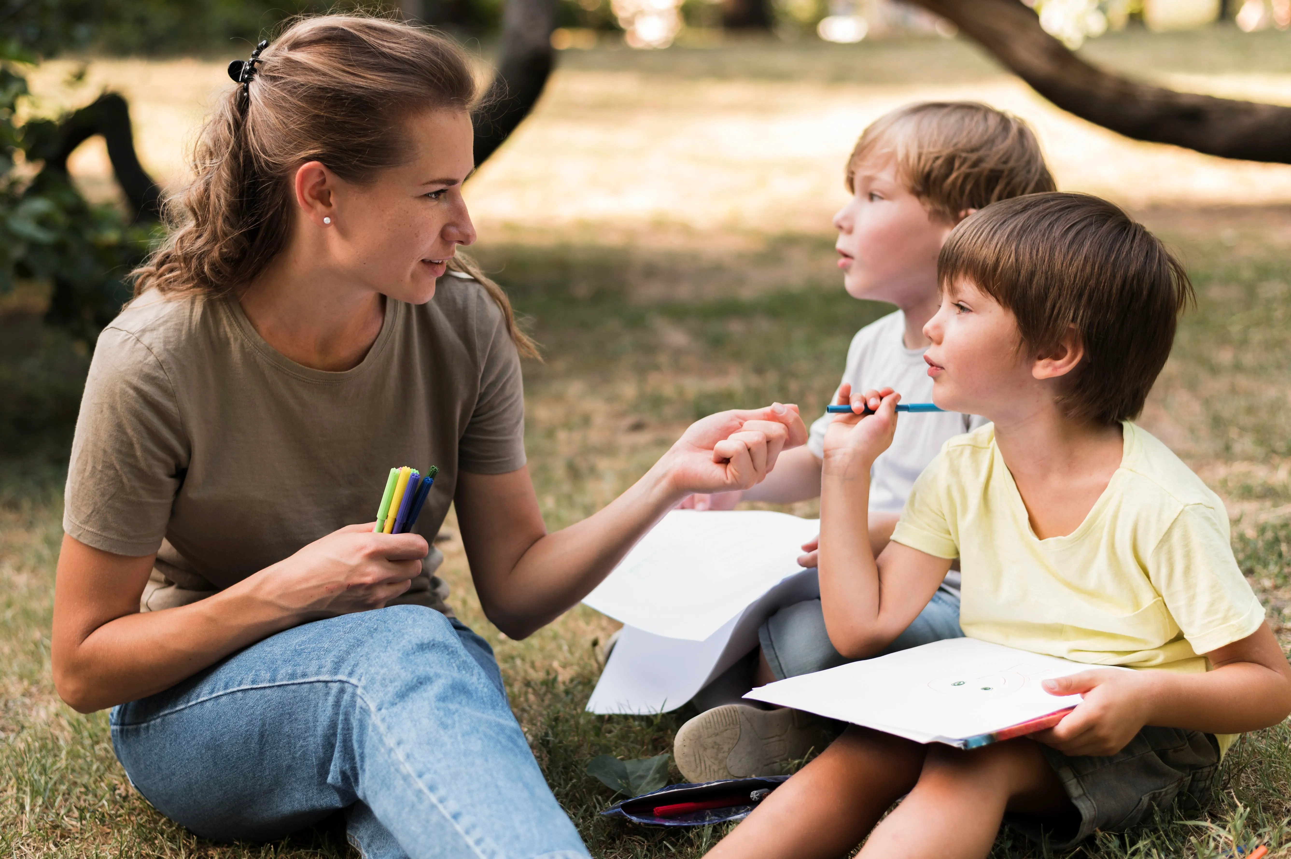 Teacher sitting on grass with children in a calm outdoor setting